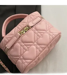 Detail of pink heart-quilted leather box bag featuring smooth gold-tone dual zippers