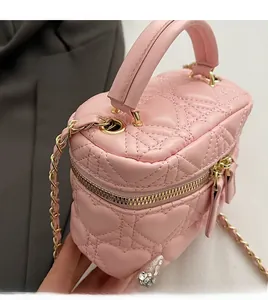 Detailed view of pink heart-quilted leather box bag with gold metal chain strap