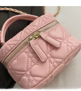 Close-up of pink heart-quilted texture with smooth gold dual zippers and leather handle