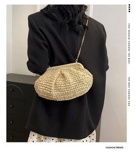 Detail of beige woven cloud bag with gold chain strap on model in elegant outfit