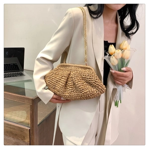 Macro detail of natural straw woven cloud bag with elegant gold metal chain strap