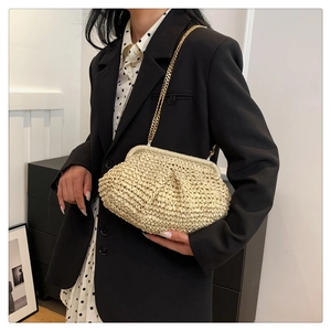 Detail of cream woven handbag featuring golden chain strap and textured fabric finish