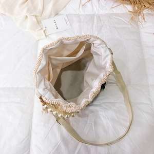 Cream straw bucket bag with white canvas interior, inner pocket and pearl chain detail