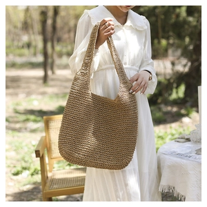 Détails du tissage à la main d'un sac cabas en paille dans un décor estival en plein air
