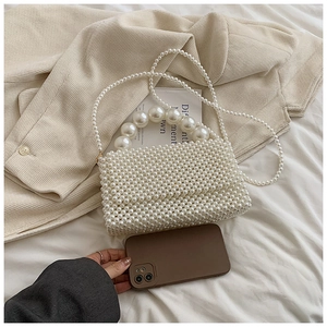 Macro detail of hand-woven white pearl handbag with large circular pearl handle