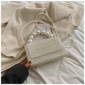 Detail view of woven pearl handbag with large beaded handle and elegant shoulder strap