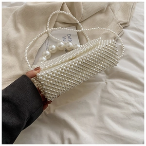 Close-up of woven pearl handbag featuring a large pearl handle and detailed texture