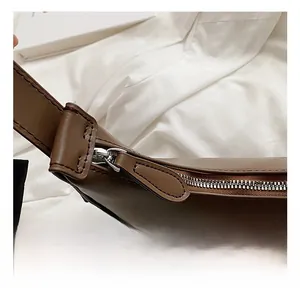 Close-up of premium silver metal zipper and smooth dark brown leather on crescent bag