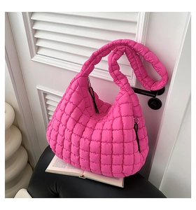 Detail of hot pink quilted puffer shoulder bag with vibrant square texture and zipper
