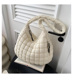 Close-up of quilted puff shoulder bag in cream finish on a black chair with minimal props