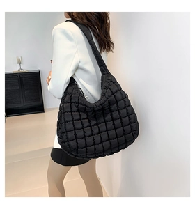 Rear side view of a black quilted puffer tote bag on a model in a modern interior setting