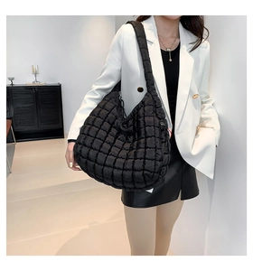 Close-up of black quilted cloud bag with puffy texture on a female model in white blazer