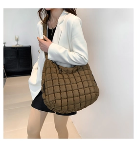 Detail of coffee brown quilted shoulder bag featuring soft puffer fabric and wide strap