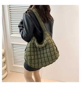 Detailed back view of an olive green quilted puffer tote bag on a female model
