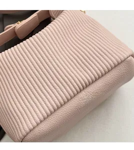 Détail du sac à main rose montrant la texture plissée verticale et la bandoulière souple