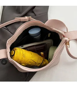 Vue de dessus de l'intérieur spacieux d'un sac bandoulière rose plissé avec objets du quotidien
