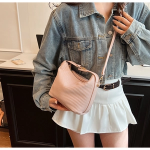 Vue détaillée de la texture du sac rose plissé avec bandoulière sur une veste en jean