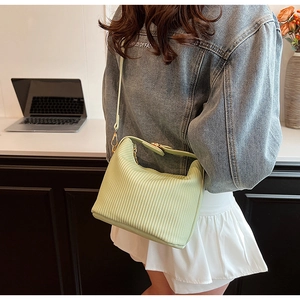 Vue détaillée d'un sac à main plissé vert clair avec texture fine sur un mannequin femme