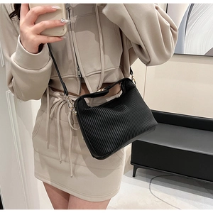 Détail d'un sac à bandoulière en cuir synthétique plissé noir avec boucles dorées