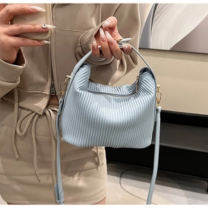 Gros plan détaillé du sac à main plissé bleu clair avec bandoulière et boucle en métal doré