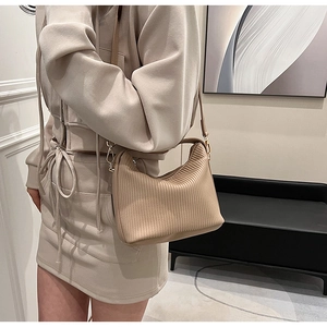 Détail d'un sac à main beige plissé avec texture verticale et finitions dorées