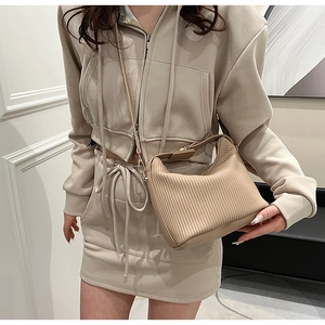 Détail du sac à main beige plissé avec boucles dorées porté en bandoulière