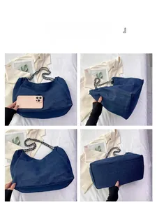 Detail view of large blue denim tote bag with metal chain straps and spacious interior
