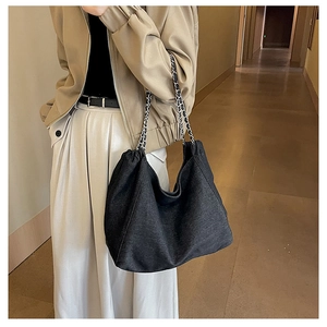 Detail of dark grey tote bag with silver metal chain strap and soft fabric texture