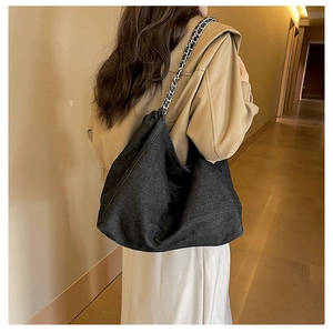 Detail of black denim hobo bag featuring slouchy design and silver chain leather strap