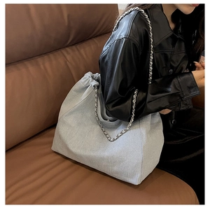 Gros plan du sac cabas en denim bleu clair avec chaîne argentée et cordon de serrage