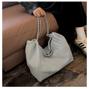Detail of light blue denim tote bag featuring a stylish silver metal chain strap