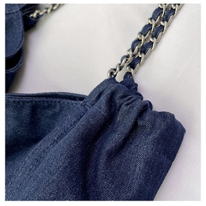 Detail of dark blue denim tote with silver metal chain straps and pleated texture