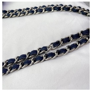 Detailed close-up of the woven metal chain strap with dark blue denim fabric texture