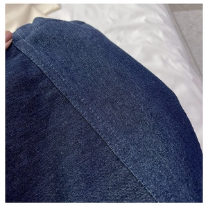Macro view of double stitching craftsmanship on high-quality dark blue denim tote bag