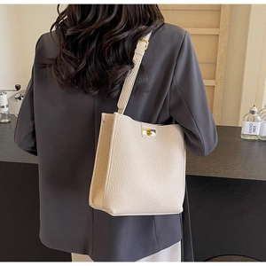 Détail d'un sac cabas en cuir beige avec bandoulière réglable et fermoir doré sur l'épaule