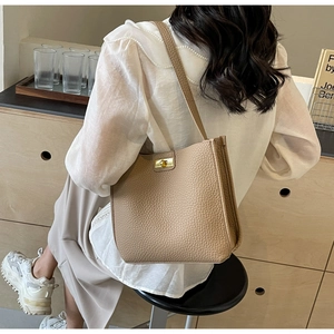 Close-up of khaki lychee grain leather bucket bag with gold rotating metal buckle lock