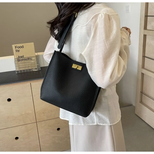 Détail du sac cabas en cuir grainé noir avec un élégant fermoir rotatif en métal doré