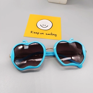 Close-up of cute apple-shaped children sunglasses with blue frames and gold metal bridge