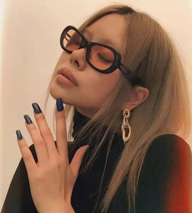 Fashion portrait of chunky black oval sunglasses with orange tinted lenses on model