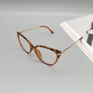 Stylish tortoiseshell cat-eye glasses frame with golden metal temples on a magazine