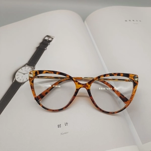 Detailed macro of tortoiseshell cat-eye frames with silver metal spring hinges on book