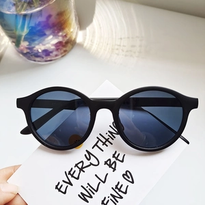 Detail shot of matte black oval sunglasses with polarized lenses on a decorative background