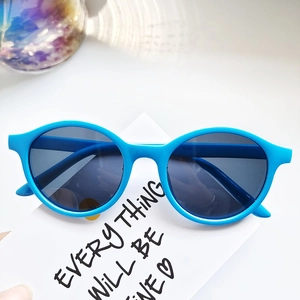 Detail view of bright blue oval sunglasses with dark lenses on a creative card background