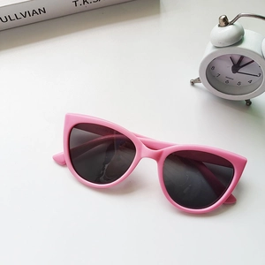 Detail of pink cat-eye children's sunglasses with dark lenses on a white background