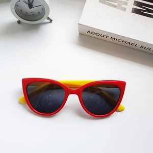 Detail of red and yellow cat-eye sunglasses with dark polarized lenses on white desk