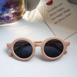 Detailed view of matte skin pink round kids sunglasses with dark protective lenses