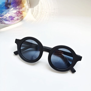 Detailed close-up of matte black round kids sunglasses with UV protection lenses