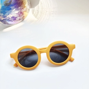 Close-up of matte yellow round children sunglasses with dark UV protection lenses