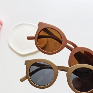 Two pairs of retro round matte kids sunglasses in earthy brown and khaki sand colors