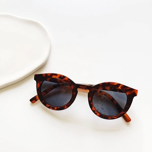 Detail of round children's sunglasses featuring retro dark brown tortoiseshell frames